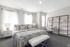 Bright and inviting bedroom with elegant decor, featuring a cozy queen-sized bed, stylish shelving unit, and ample natural light.