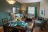 Elegant living and dining area with chic teal accents, showcasing a cozy seating arrangement and sophisticated dining setup.