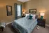 Inviting bedroom with elegant decor, featuring a plush bed with teal accents, ambient lighting, and artistic wall pieces.