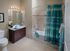 Modern bathroom featuring elegant tiles, a spacious vanity with a mirror, and a stylish shower area with blue accents.