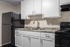 Contemporary kitchen with sleek black appliances, elegant marbled countertop, and modern white cabinetry.