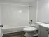 Modern bathroom featuring sleek white tiles, an inviting bathtub, and stylish wood flooring.