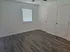 Bright and airy room with modern wood flooring, white walls, and abundant natural light from a window with blinds.