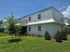 Charming two-story white apartment building with lush green landscaping and modern architectural design.