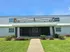Charming apartment entrance with a welcoming path, well-kept shrubs, and a bright facade under a clear blue sky.