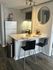 Charming modern kitchen with elegant white countertops, stylish bar seating, and sleek appliances, perfect for entertaining.