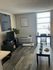 Contemporary and cozy living room with stylish decor, featuring a modern entertainment center, lush indoor plant, and bright natural light through large windows.
