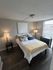 Chic bedroom with warm lighting, elegant decor, and large windows offering abundant natural light.