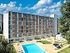 Modern apartment complex with stunning architecture, lush greenery, and a sparkling swimming pool under a bright blue sky.