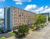 Contemporary apartment building with modern architecture, surrounded by lush greenery in an urban setting, offering vibrant city living.