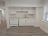 Charming kitchenette with sleek white cabinetry and modern appliances, complemented by elegant wood flooring and ample natural light.