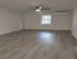 Spacious room with elegant wood flooring, modern ceiling fan, and ample natural light from a large window.