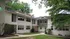 Charming white brick apartment complex surrounded by lush greenery, featuring modern architectural design and inviting entryway.
