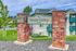 Welcoming Maple Valley sign with vibrant brick pillars, lush green surroundings, and modern apartment buildings in the background.