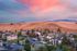 Charming suburban apartment complex nestled against rolling golden hills, with vibrant sunset sky creating a picturesque and serene environment.
