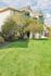 Charming apartment building with vibrant green lawns and inviting balconies, set under a beautiful blue sky.