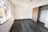 Bright and inviting bedroom with elegant dark wooden flooring, ample natural light from a large window, and spacious closet with sliding doors.