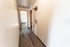Inviting hallway with elegant wood-style flooring and in-unit laundry area, leading to a light-filled room, ideal for modern living.