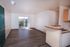 Bright living area with modern hardwood floors and natural light from a balcony view, adjacent open kitchen with sleek counter design.