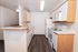 Bright, modern kitchen showcasing sleek white appliances, ample cabinetry, and stylish wood flooring.