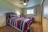 Inviting bedroom with double beds adorned in vibrant striped comforters, featuring a cozy carpet and a ceiling fan for comfort.