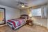 Cozy bedroom featuring a comfortable bed with stylish striped bedding, a modern ceiling fan, and natural light streaming through the window.
