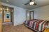 Inviting bedroom with modern ceiling fan, chic striped bedding, and a view of the cozy carpeted hallway.
