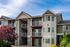 Charming apartment complex with modern architecture, private balconies, and lush landscaping on a sunny day.