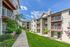 Charming apartment complex with modern facades, inviting balconies, and vibrant landscaping under a sunny blue sky.