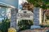 Elegant entrance sign for Churchill Downs Apartments featuring a stone column and lush greenery.