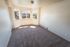 Bright and inviting room with large windows, plush carpet, and serene outside view, perfect for comfortable living.