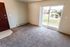 Inviting living room with plush carpeting and abundant natural light from large sliding glass doors leading to a balcony with scenic views.