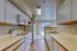 Bright and modern kitchen with white cabinetry, sleek countertops, and a window view of green landscape.