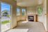 Inviting sunlit living room featuring a cozy fireplace, large windows with scenic views, and a plush carpet floor.