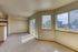 Bright and airy living space with large windows, plush carpet, and access to a sunny balcony, offering serene views of a landscaped courtyard.