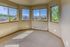 Bright and inviting corner room with large windows offering beautiful views of lush greenery and neighboring buildings.