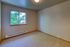 Bright empty room with plush carpet, large window showcasing serene greenery, and soft neutral walls, perfect for personalization.