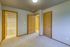 Bright and inviting room showcasing soft carpet flooring, light wood doors, and access to a modern bathroom.