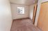 Inviting bedroom with plush carpet, large window offering natural light, and sleek wooden closet doors.
