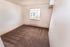 Bright, unfurnished room with soft carpet and a large window, offering a cozy and inviting atmosphere.