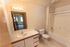 Bright and modern bathroom featuring elegant lighting, a spacious bathtub, and a stylish vanity with ample storage.