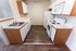 Modern kitchen with sleek wooden cabinets, stainless steel sink, and white appliances, featuring stylish wood flooring.