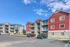 Vibrant apartment complex featuring modern multi-story buildings with colorful facades and ample parking under a clear blue sky.