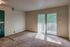 Bright, inviting room with plush carpet, floor-to-ceiling windows, and balcony view overlooking lush greenery.