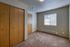 Bright and cozy bedroom featuring warm wood accents, soft carpets, and ample natural light from a sunny window.