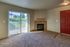 Inviting living room with a cozy fireplace, plush carpet, and sliding glass door leading to a serene balcony.