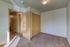 Cozy bedroom with plush carpet, ample natural light, and wooden closet doors, offering a warm and inviting atmosphere.