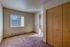 Bright and cozy bedroom with large window, beige carpeting, and ample closet space.