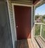 Charming apartment balcony with wooden flooring, overlooking a vibrant community and lush greenery.