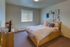 Cozy bedroom with soft lighting, featuring a comfortable bed adorned with plush pillows, warm decor, and a charming wall gallery.
